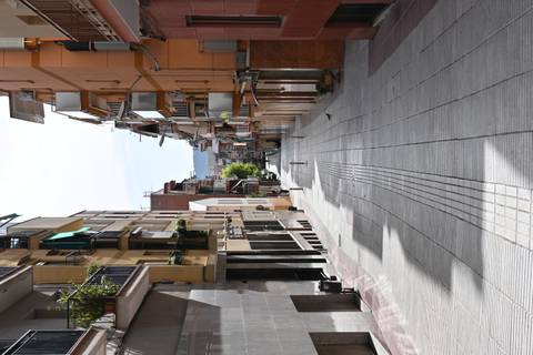 An empty urban street with narrow buildings under bright daylight.
