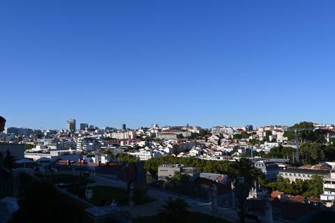 A panoramic cityscape view with clusters of white and red roofed buildings.