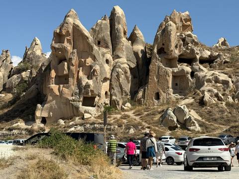 People walking towards unique rock formations that have cave-like structures.