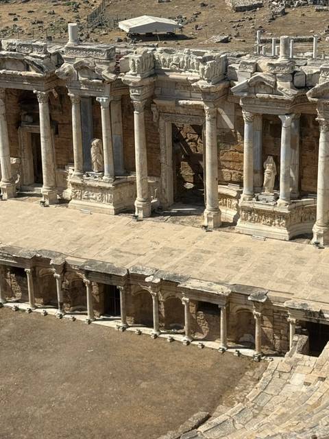 An ancient stone theater with columns and statues, capturing classical architecture.