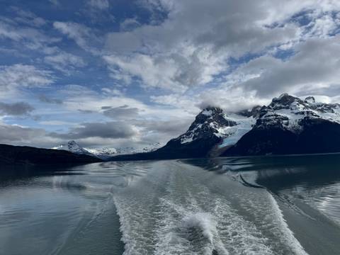 View from a boat cruising towards snow-capped mountains and glaciers.