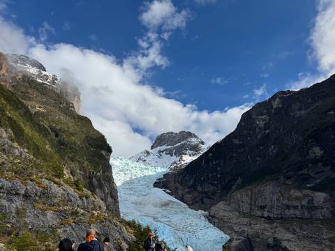 Close-up view of a glacier nestled between mountain cliffs under a blue sky.