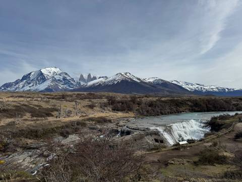 Stunning waterfall and mountain range with a clear blue sky.