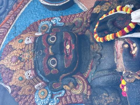       Black stone statue adorned with colorful flowers.
  