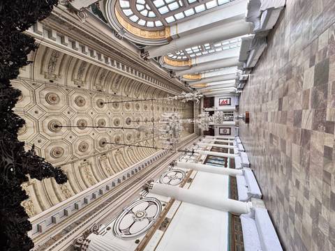 Elegant interior of a historic building with chandeliers and large windows.