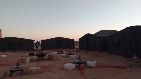       Desert camp setting in Morocco with tents and seating arrangements.
  