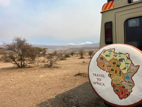 African landscape with a vehicle showing a map of Africa.