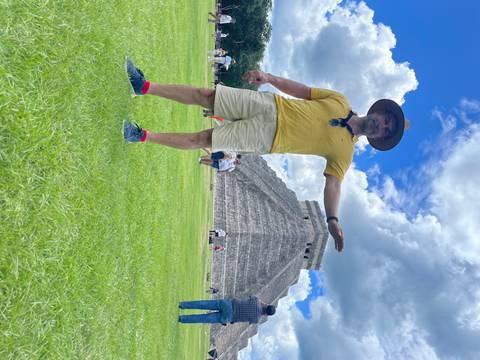       A person posing with an ancient pyramid in the background.
  