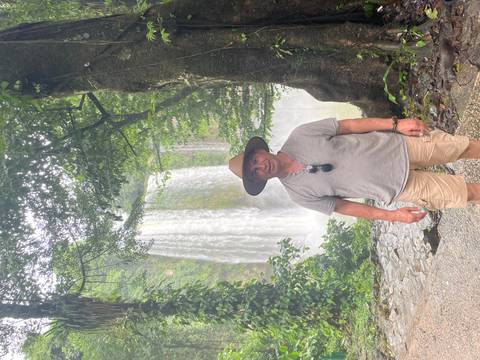 Person posing in front of a waterfall.