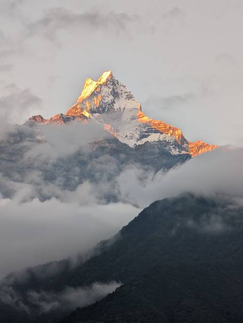 Mountain peak with clouds illuminated by sunset.