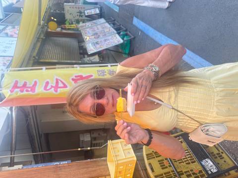       Woman eating street food near market stalls.
  