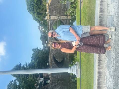       Couple posing by a historic bridge with a castle.
  