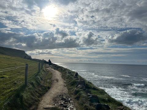       Coastal path with waves and a cloudy sky.
  