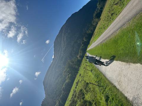 Cyclists riding on a path beside a mountainous area.