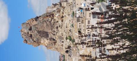 A large rock formation with dwellings at its base.
