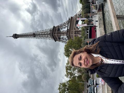 Woman smiling in front of the Eiffel Tower in Paris.