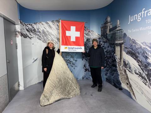       Couple posing with the Swiss flag at Jungfraujoch.
  