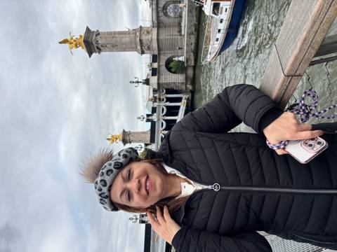 Woman smiling on a bridge with decorative statues in Paris.