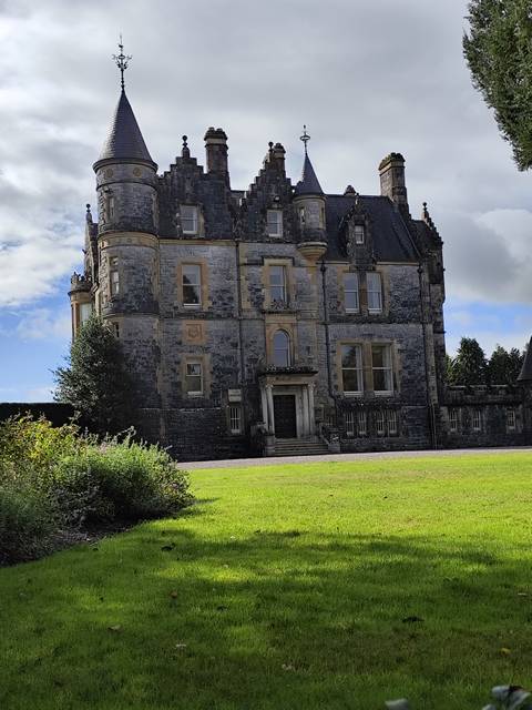 Large stone mansion with lush lawn and trees, Ireland.