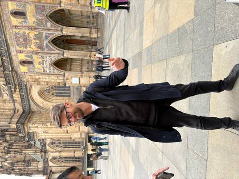 Man posing in front of a historic building, Prague.