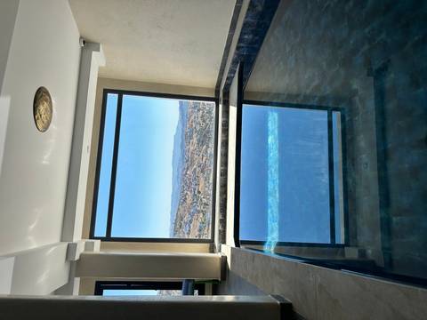 Indoor pool with a view of a Moroccan town through large window.