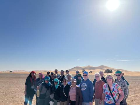 A large group of people posing in the desert.
