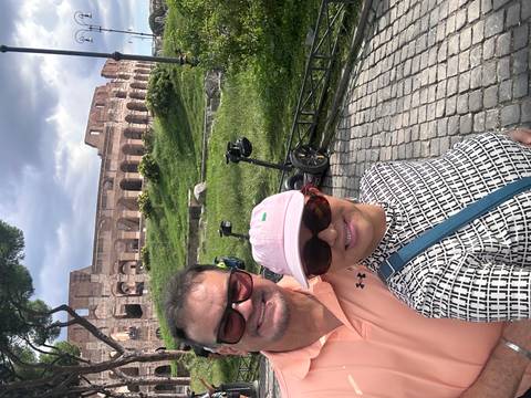       A couple taking a selfie with the Colosseum in the background.
  