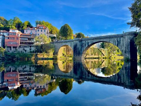 A stone bridge over a calm river with reflections.