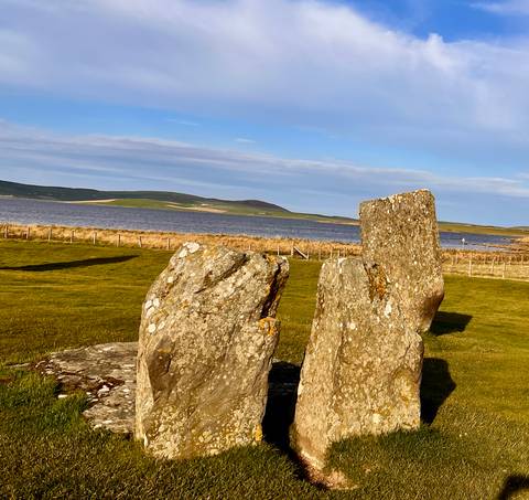 Distant view of a stone circle near a body of water.