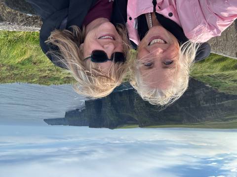 Two women posing in front of the Cliffs of Moher.