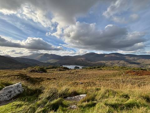 Scenic vista of mountains and a lake with clouds in the sky.