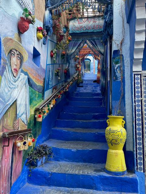      Colorful stairway in Chefchaouen with artworks and flowers.
  