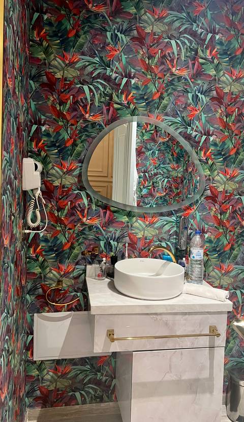 Colorful bathroom with a leaf-patterned wall and modern sink.