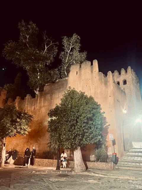 Fortified clay walls of a historic structure at night.