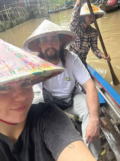 People in a traditional boat with a person paddling in a waterway.