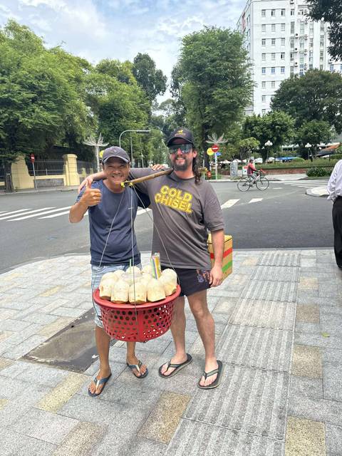 Two men smiling at the camera with a street food setup.