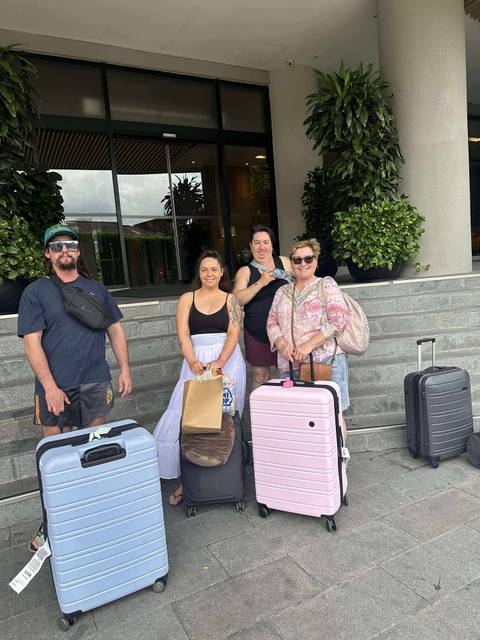       Group photo of people with luggage outside a building.
  