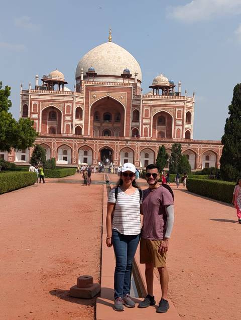 Tourists posing in front of a large historic building with arches.