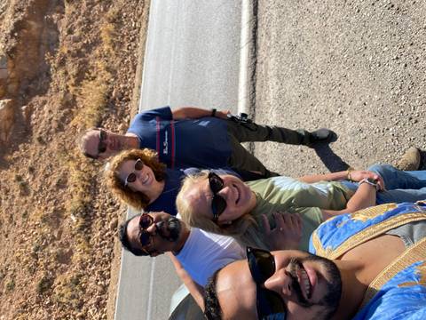 Five people taking a group selfie near a rocky roadside.