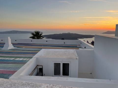 View over a rooftop towards the sea at sunset.