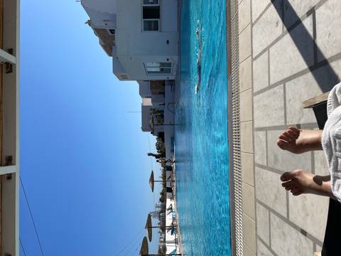 Person's feet with a view of a swimming pool and lounging area.