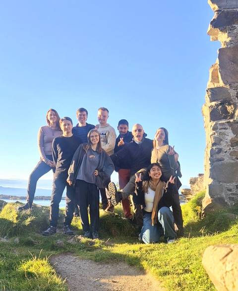 Group of people posing next to stone ruins.