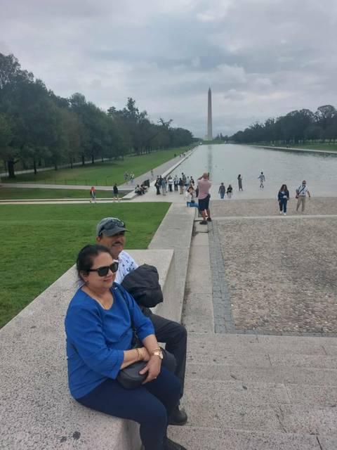 People sitting by a large reflecting pool, overcast sky.