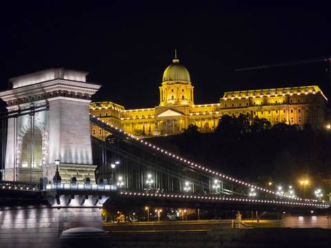       A beautifully lit castle and bridge at night.
  