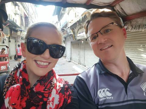A smiling couple taking a selfie in a market alley.
