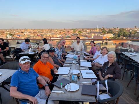 Group of people dining on a rooftop with a view of a cityscape.