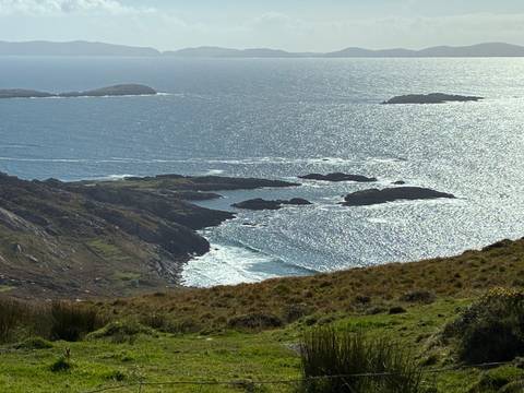 A coastal view with small islands and the sun reflecting on the ocean.