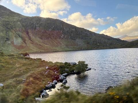 A tranquil lake surrounded by hills and partial sunlight.