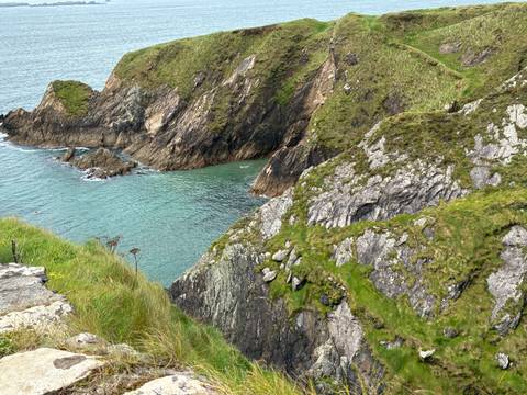 A rugged coastline with turquoise waters meeting rocky cliffs.