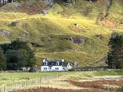       A small house nestled in a rural, hilly landscape.
  